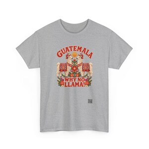 Puede incluir: Una camiseta gris jaspeado de manga corta con un gr&aacute;fico de dos llamas frente a frente, rodeadas de flores coloridas y un sol. El texto dice GUATEMALA en la parte superior y WHY NO LLAMA? en la parte inferior en letras rojas.