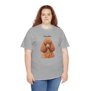 May include: A heather gray short-sleeve t-shirt featuring a centered graphic of a brown curly-haired poodle. Above the dog illustration, the word Poodle is printed in a simple black sans-serif font. The shirt has a crew neckline and a standard fit.