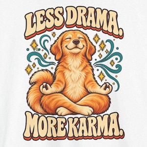 May include: A white graphic print featuring a golden-colored dog sitting in a lotus meditation pose with eyes closed. The text "LESS DRAMA." appears above the dog and "MORE KARMA." below, surrounded by teal swirling lines and yellow star shapes.