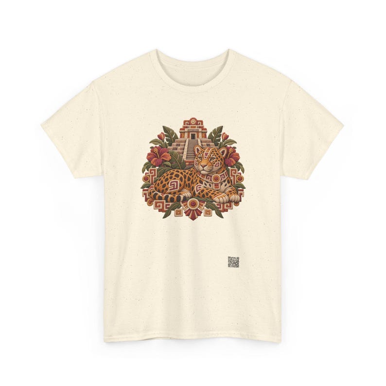 May include: A cream-colored t-shirt featuring a central graphic of a spotted jaguar resting in front of a stepped pyramid, surrounded by red hibiscus flowers and green leaves, with a small square QR code printed near the bottom right.