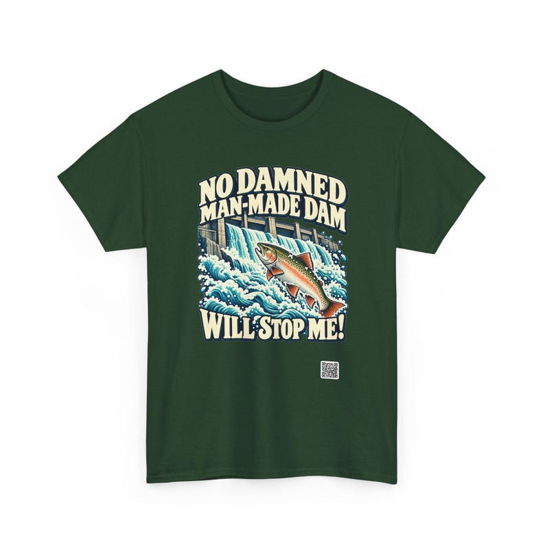 Puede incluir: Una camiseta verde oscuro con un gr&aacute;fico de un pez saltando sobre una presa y el texto NO DAMNED MAN-MADE DAM WILL STOP ME! en letras color crema sobre y bajo la ilustraci&oacute;n, adem&aacute;s de un peque&ntilde;o c&oacute;digo QR en la parte inferior.