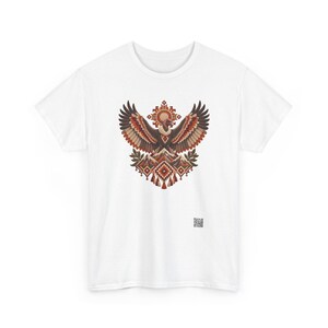May include: A white short-sleeved t-shirt featuring a central graphic of a vulture with wings spread wide above a mountain range. The design incorporates geometric patterns in shades of brown, orange, and cream, with a small QR code at the bottom.