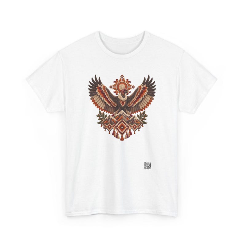 May include: A white short-sleeved t-shirt featuring a central graphic of a vulture with wings spread wide above a mountain range. The design incorporates geometric patterns in shades of brown, orange, and cream, with a small QR code at the bottom.