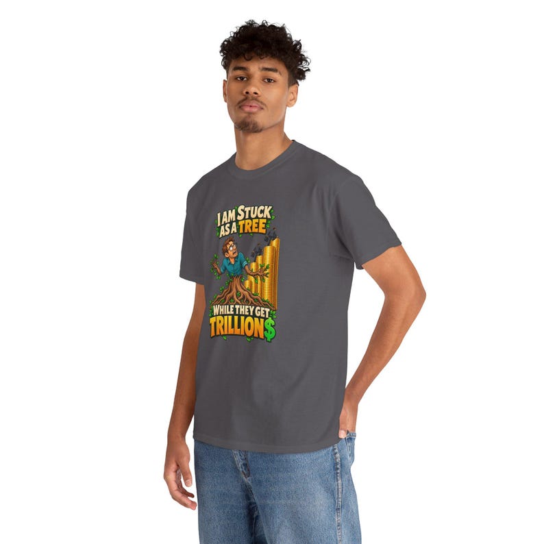 May include: A dark gray short-sleeve t-shirt featuring a graphic of a person transformed into a tree with the text "I AM STUCK AS A TREE WHILE THEY GET TRILLION$" in yellow and green lettering, alongside tall gold bars.