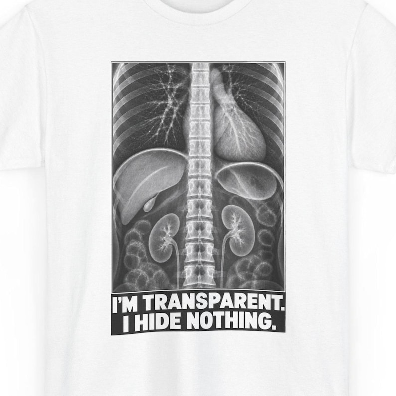 Puede incluir: Una camiseta blanca con un gr&aacute;fico en blanco y negro de una radiograf&iacute;a del torso humano que muestra la columna vertebral, los pulmones y los &oacute;rganos internos. Debajo, el texto en may&uacute;sculas dice: I'M TRANSPARENT. I HIDE NOTHING.