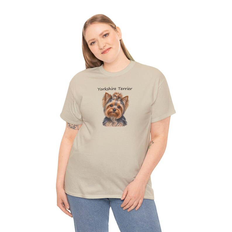 Op de afbeelding: Een beige t-shirt met korte mouwen voorzien van een gecentreerde grafische illustratie van een Yorkshire Terri&euml;r met de tekst "Yorkshire Terrier" in zwarte letters boven de kop van de hond op de voorzijde.