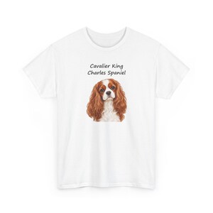 Puede incluir: Una camiseta blanca de manga corta con un gr&aacute;fico central de un perro Cavalier King Charles Spaniel marr&oacute;n y blanco. Sobre la ilustraci&oacute;n del perro, el texto dice Cavalier King Charles Spaniel en una fuente negra sencilla.