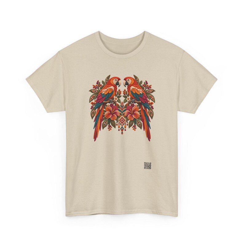 May include: A beige short-sleeved t-shirt featuring a central graphic of two symmetrical parrots perched among red hibiscus flowers and green foliage. The design includes intricate patterns and a small square QR code at the bottom right.