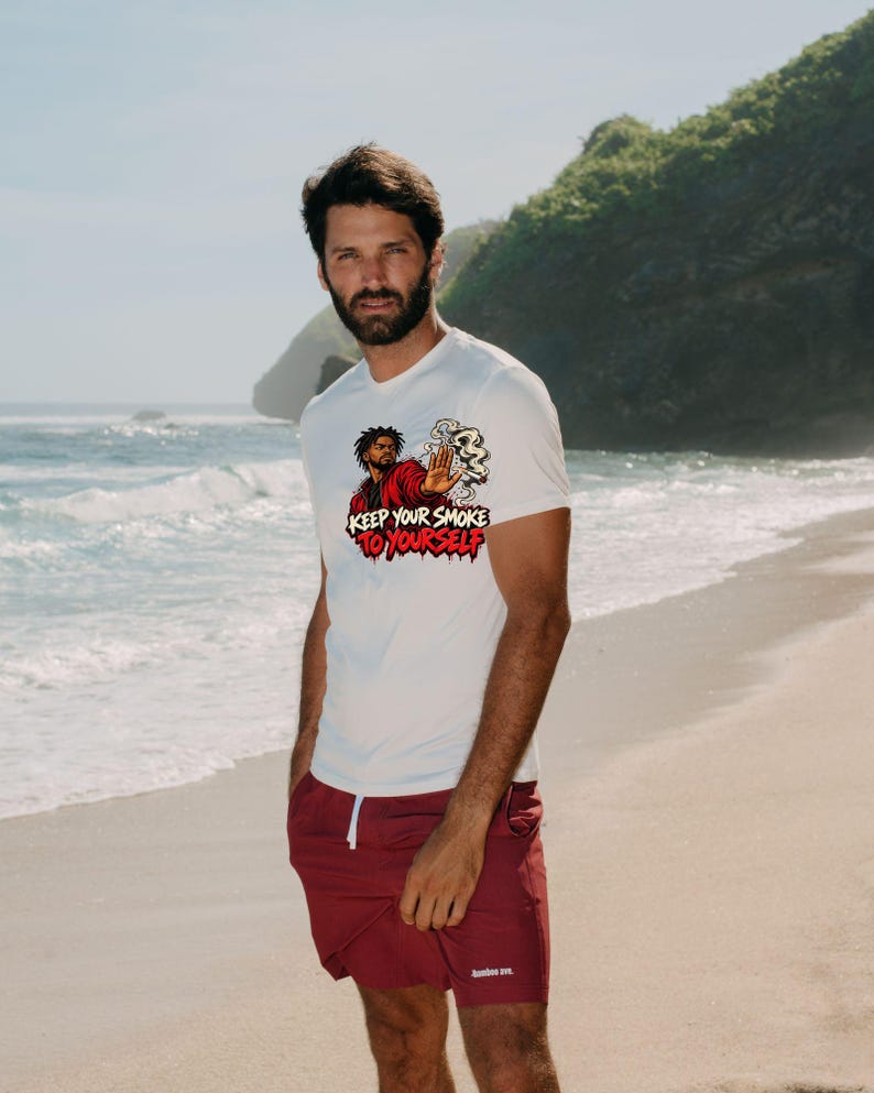 May include: A white short-sleeved t-shirt featuring a graphic of a person in a red jacket holding a smoking item with a hand raised in a stop gesture, accompanied by the text "KEEP YOUR SMOKE TO YOURSELF" in bold red and black lettering.