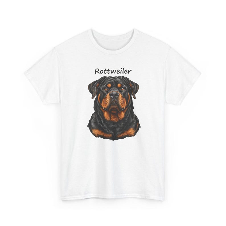 May include: A white short-sleeved t-shirt featuring a centered graphic illustration of a Rottweiler dog head with black and tan fur. Above the dog illustration, the word Rottweiler is printed in a simple black sans-serif font.