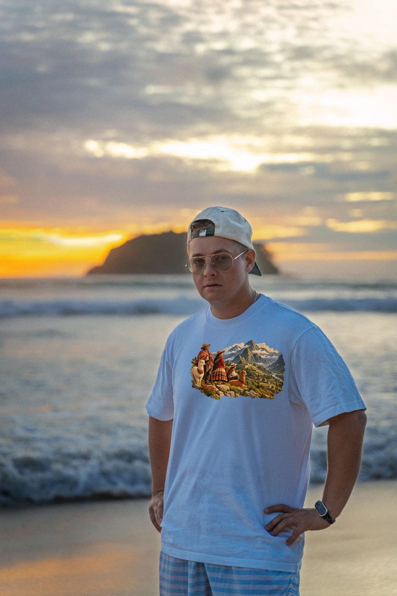 May include: A white short-sleeved t-shirt featuring a colorful graphic print of people in traditional clothing with llamas in a mountainous landscape. The shirt is worn with a light-colored baseball cap and round-framed glasses.