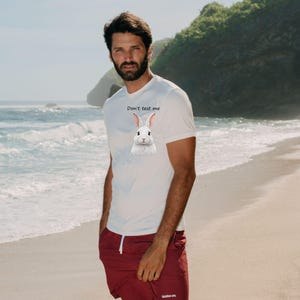 May include: A white short-sleeved t-shirt featuring a graphic of a white rabbit and the text "Don't test me" printed on the chest, paired with maroon shorts that have a white drawstring and a small white logo on the lower left leg.