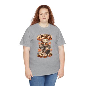 K&ouml;nnte beinhalten: Ein graues, kurz&auml;rmeliges T-Shirt mit einer Grafik eines laufenden Roboters in Orange und Wei&szlig;. Der Text &uuml;ber dem Roboter lautet AUTOPILOT MODE und der Text darunter lautet CLEAR THE WAY in einer fetten, orangefarbenen Schriftart.