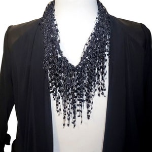 May include: A black beaded necklace with a fringe design. The necklace is worn on a mannequin wearing a black blazer.