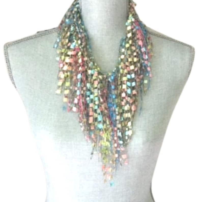 May include: A multi-colored crocheted scarf with a fringe. The scarf is made of a variety of shades of blue, green, pink, and brown.
