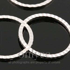 May include: Two silver metal rings with a textured, ridged surface. The rings are overlapping.