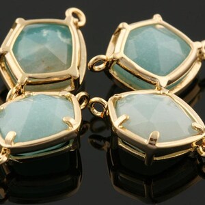 Puede incluir: Cuatro abalorios conectores de metal dorado con piedras de vidrio facetadas de color azul claro. Cada abalorio tiene dos lazos para sujetar a las joyas.