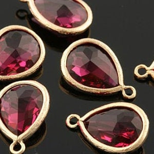 May include: Six teardrop-shaped, faceted, dark pink glass beads with gold-toned metal settings and jump rings.