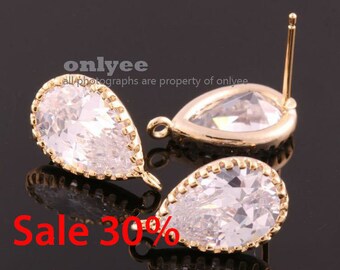 May include: Two gold teardrop-shaped earring findings with clear faceted crystals. The findings have a loop at the top for attaching to an earring post.
