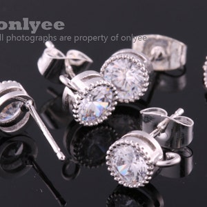 May include: Four silver earring findings with clear crystal stones. Each finding has a post and a loop for attaching a charm or pendant.