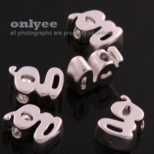 May include: Silver charm beads in the shape of the letters "LOVE" with a sparkly stone in each letter. The beads are designed for use in jewelry making.