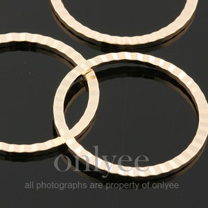 May include: Three gold-coloured metal rings with a textured, ridged surface. The rings are stacked on top of each other.