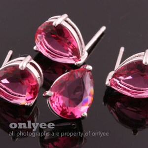 May include: Three pairs of silver teardrop earrings with pink crystal stones.
