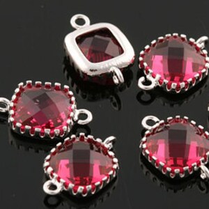 May include: A group of five red crystal square connectors with silver metal frames and loops. The connectors are for jewelry making.