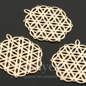 Puede incluir: Tres dijes de metal dorado con un patrón de flor geométrico. Los dijes son redondos y tienen un diseño delicado e intrincado.