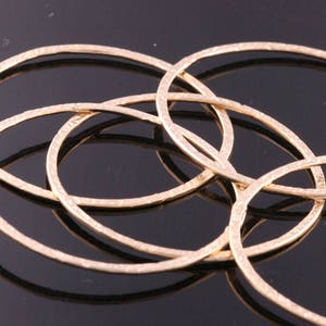 May include: Five gold-toned metal hoops with a textured surface. The hoops are stacked and overlapping.