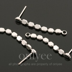 May include: Three silver earring findings with a row of small, faceted, silver beads. Each finding has a loop at one end and a post at the other end.