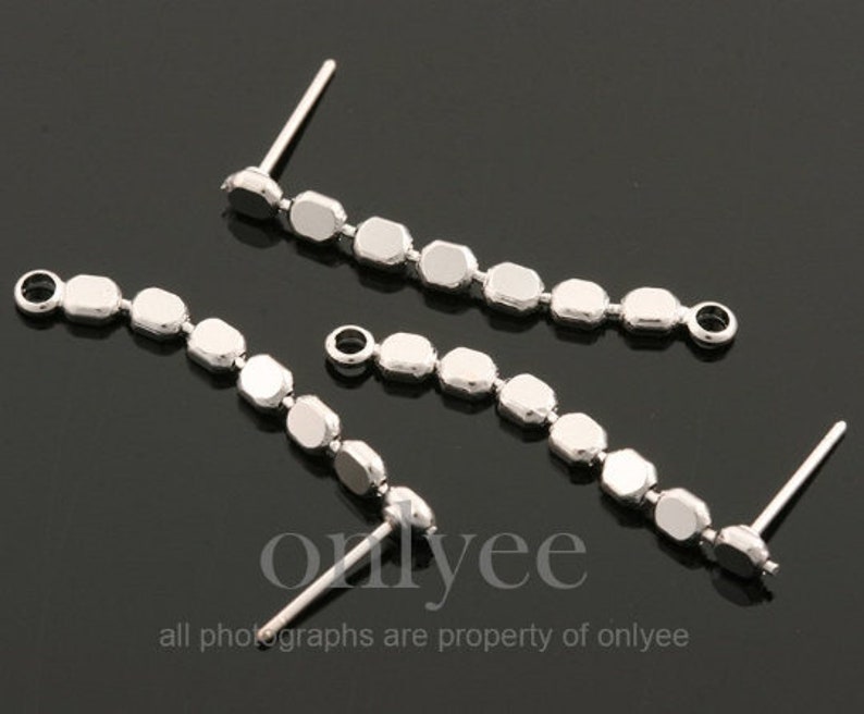 May include: Three silver earring findings with a row of small, faceted, silver beads. Each finding has a loop at one end and a post at the other end.