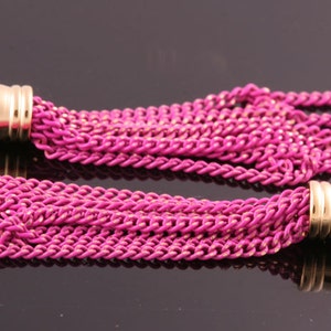 May include: Two pink tassel earrings with gold metal caps. The tassels are made of multiple strands of chain.