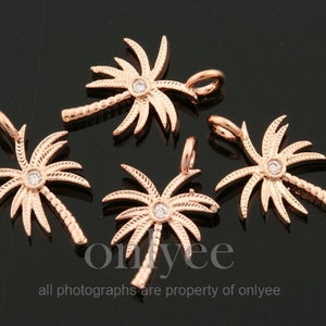 May include: Five rose gold palm tree charms with clear rhinestone accents. Each charm has a loop for attaching to a necklace or bracelet.