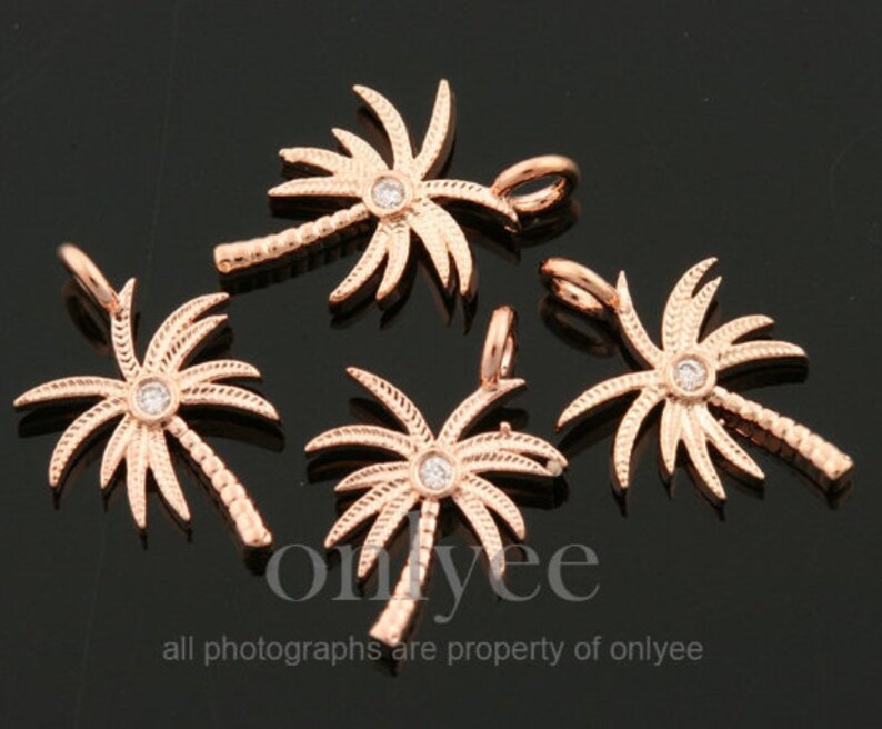 May include: Five rose gold palm tree charms with clear rhinestone accents. Each charm has a loop for attaching to a necklace or bracelet.