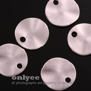 May include: Five silver-colored metal circles with a hole in the center. The circles have a slightly textured surface.
