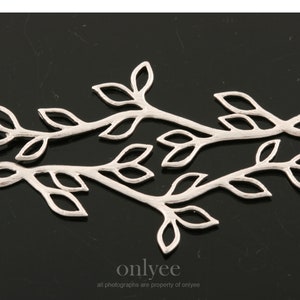 May include: Three silver metal leaf branch connectors, each with a loop at one end. The connectors are designed to be used in jewellery making or other craft projects.