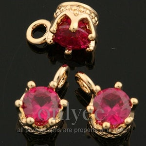 Pode incluir: Três pingentes de tom dourado com detalhes em cristal vermelho. Cada pingente apresenta um design de coroa com um cristal vermelho redondo no centro.