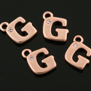 Puede incluir: Cuatro abalorios con la letra G en oro rosa con un strass transparente en el centro de cada abalorio.