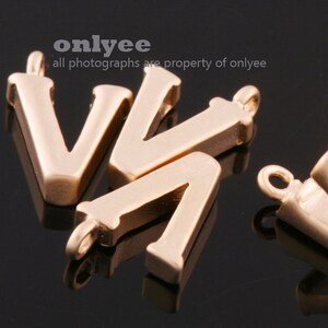 May include: Gold-colored metal letter V charms. The charms have a simple, classic design and are perfect for adding a personalized touch to jewelry or crafts.