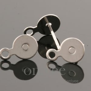 May include: Two silver earring backs with a small loop on the side. The backs are round with a flat surface.