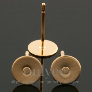 May include: Three gold-colored earring posts with flat round backs. The posts are made of metal and have a smooth finish.