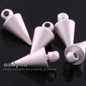 May include: Five silver-coloured metal cone-shaped charms with a pointed tip. The charms have a hole at the top for attaching to jewellery or other crafts.