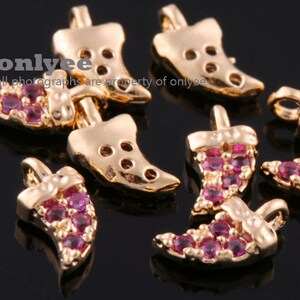 May include: Gold-tone charms shaped like Christmas stockings with pink rhinestones. The charms are ideal for jewellery making or adding a festive touch to crafts.