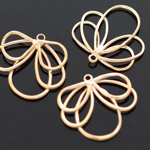 May include: Three gold metal flower-shaped charms with a loop at the top for attaching to jewelry or other crafts.