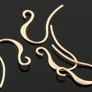 May include: Four gold-toned earring hooks with a curved design. The hooks are made of metal and have a shiny finish.