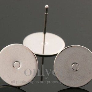 May include: Two silver earring blanks with a post and a round base. The blanks are designed to be used for making custom earrings.