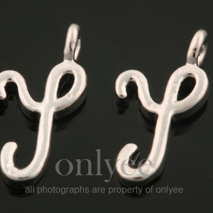 May include: Two silver charm pendants in the shape of the letter 'y' in a cursive script font.