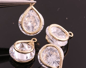 May include: Four gold-tone teardrop-shaped pendants with clear crystal stones. Each pendant has a small loop at the top for attaching to a chain or other jewelry.