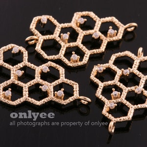 May include: Three gold-toned metal charms shaped like honeycombs with clear rhinestones. Each charm has a loop for attaching to jewelry.